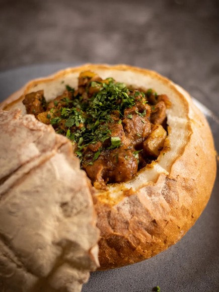 Các loại cà ri nhân bunny chow bày trong nồi tại quán ăn